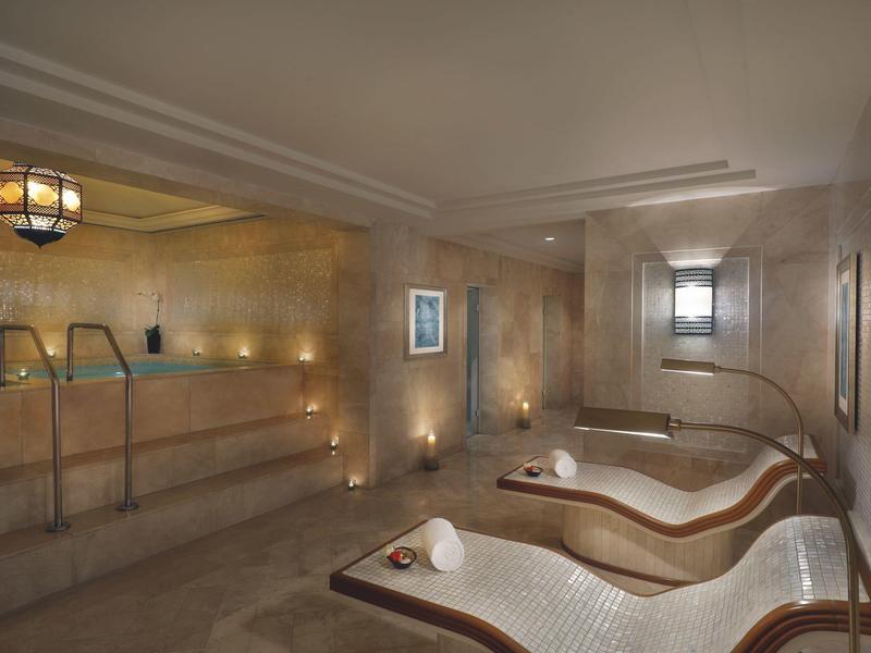 Vista interior de una zona de spa con jacuzzi, tumbonas e iluminación suave.