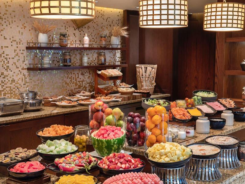 Buffet con varias frutas y pasteles en un acogedor restaurante de hotel.