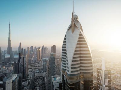 Panoramiczny widok na nowoczesną panoramę Dubaju o zachodzie słońca z charakterystyczną futurystyczną wieżą na pierwszym planie.