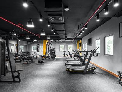 Moderner Fitnessraum mit Laufbändern, Hanteln und Kraftgeräten in einem hellen Raum.