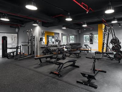 Moderner Fitnessraum mit Gewichten, Hantelbänken und Spiegeln in einem Hotel.