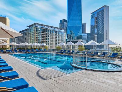 Nowoczesny basen hotelowy z parasolami i leżakami w mieście z wysokimi budynkami