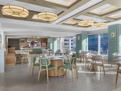 Modernes Restaurant mit hellen Holzmöbeln und großen Fenstern mit Blick auf die Stadt.