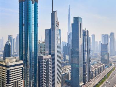 Vista di grattacieli moderni e un'autostrada in una città sotto un cielo azzurro.