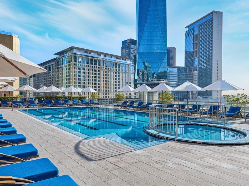 Nowoczesny basen hotelowy z parasolami i leżakami w mieście z wysokimi budynkami