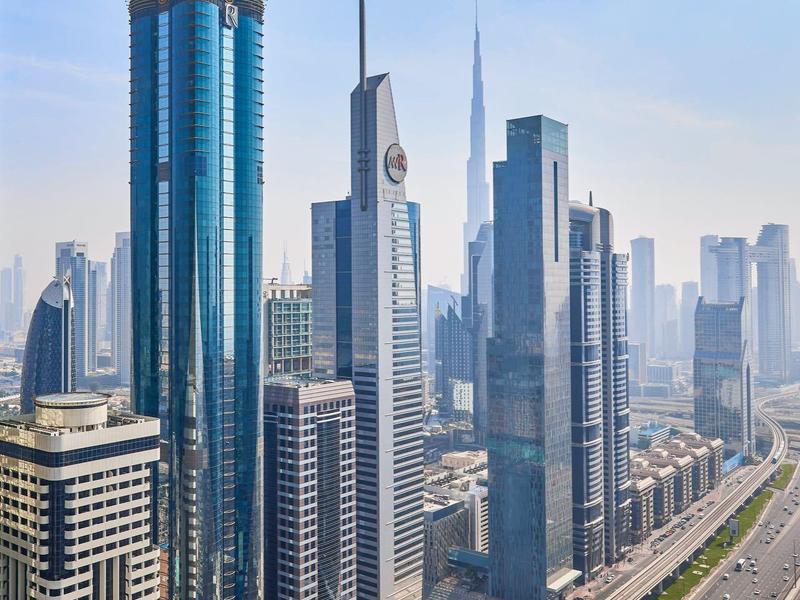 Widok na nowoczesne drapacze chmur i autostradę w mieście pod bezchmurnym niebem.