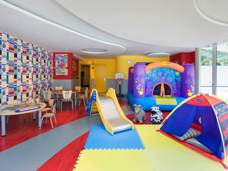 Bunter Kinderspielraum mit Rutsche, Zelt und Spielsachen, ideal für Familien im Hotel.