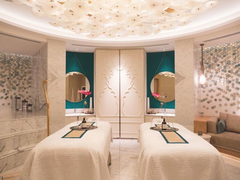 Eleganter Spa-Raum mit zwei Massageliegen, runden Spiegeln und sanfter Beleuchtung.