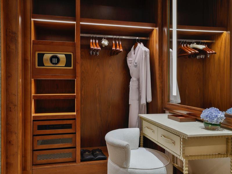 Eleganter Kleiderschrank mit Bademantel und Schminktisch in warm beleuchtetem Zimmer.