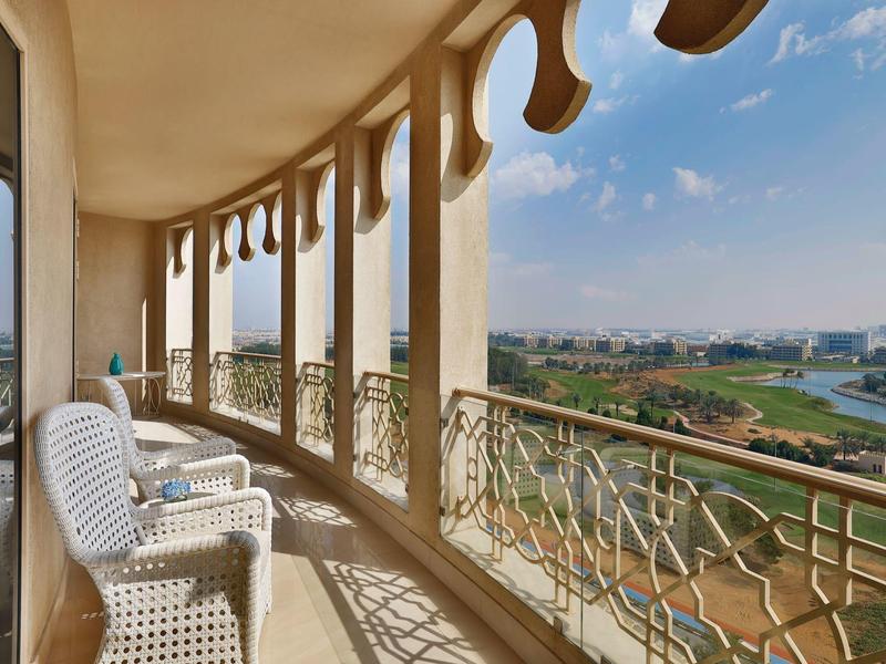 Balkon mit weißen Stühlen und Blick auf eine Grünfläche und Stadtlandschaft