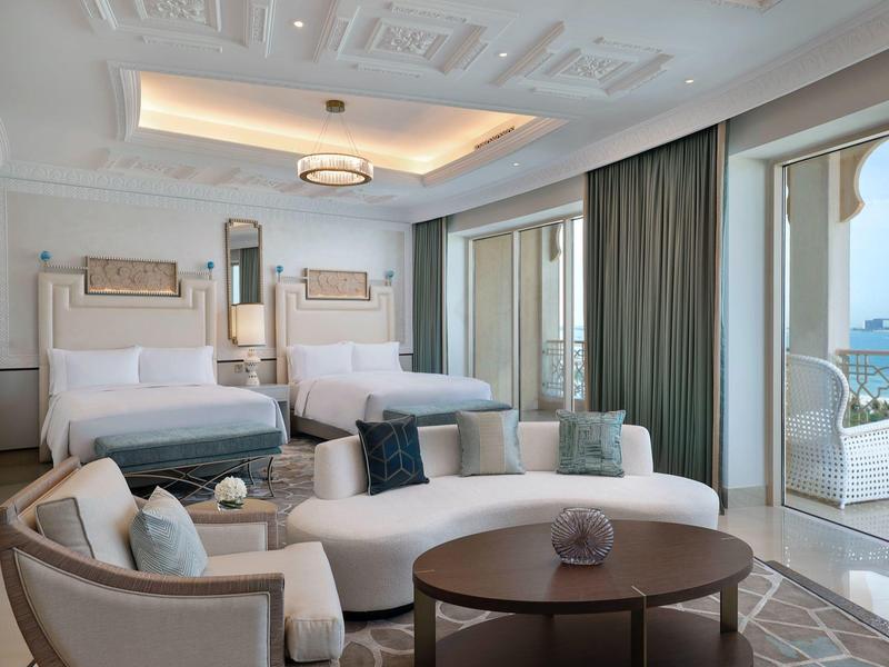 Elegantes Hotelzimmer mit zwei Betten, Sitzbereich und großem Balkon mit Meerblick.