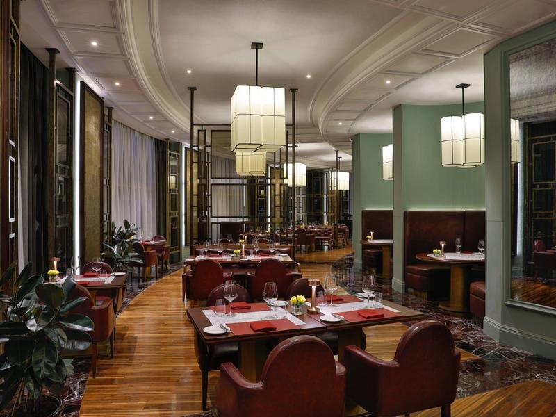 Elegantes Restaurant mit Holzboden, roten Stühlen und modernen Lampen in einem Hotel.