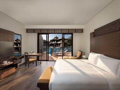 Chambre d'hôtel moderne avec grand lit, bureau et vue sur la piscine et les bâtiments