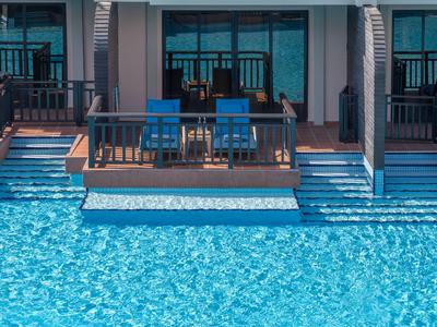 Deux chaises longues bleues sur une terrasse avec accès direct à une piscine bleue claire.