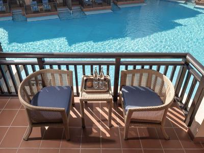 Deux chaises et une table avec du champagne devant une piscine bleue sur une terrasse.