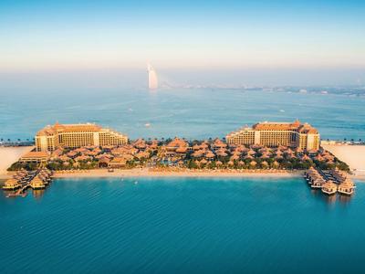 Luftaufnahme eines luxuriösen Strandresorts mit zwei großen Hotels und mehreren Bungalows.