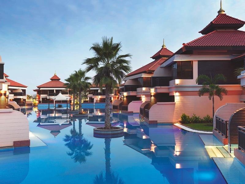 Luxuriöse Resortanlagen mit Pool, Palmen und asiatisch inspirierten Pagodendächern bei klarem Himmel.