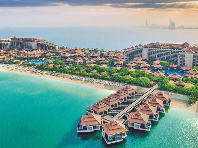 Luxuriöses Resort mit Wasservillen, Strand, grünen Gärten und großen Hotelgebäuden an der Küste.