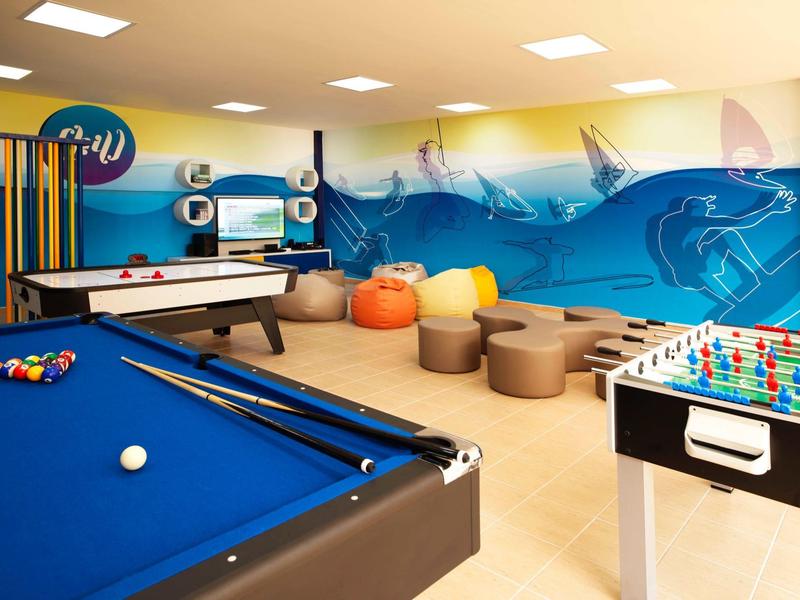 Spielzimmer mit Poolbillard, Kicker, Billardtisch, Sitzsäcken und Wandgestaltung mit Unterwasser-Motiv.