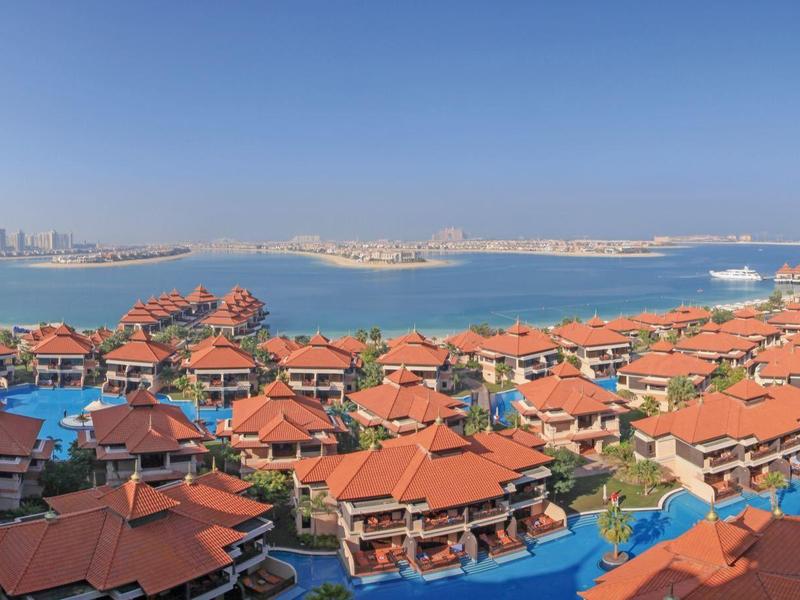 Blick auf rote Dächer, blaue Wasserflächen und einen bewölkten Himmel am Küstengebiet.