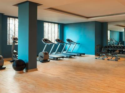 Moderner Fitnessraum mit Cardio-Geräten und Hanteln, hell und geräumig.