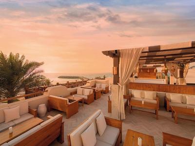 Dachterrasse mit Sitzgelegenheiten und Blick auf das Meer bei Sonnenuntergang.