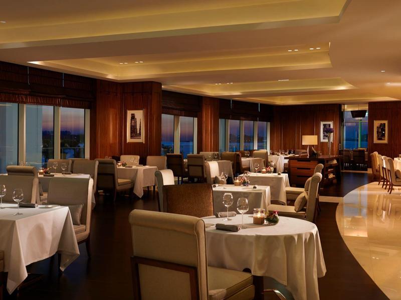 Elegantes Restaurant mit weißen Tischdecken, bequemen Stühlen und warmem Holzdekor.