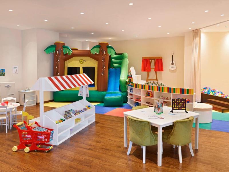 Heller, geräumiger Spielraum mit buntem Spielturm, Holzmöbeln, Teppichen und Kinderspielzeug.