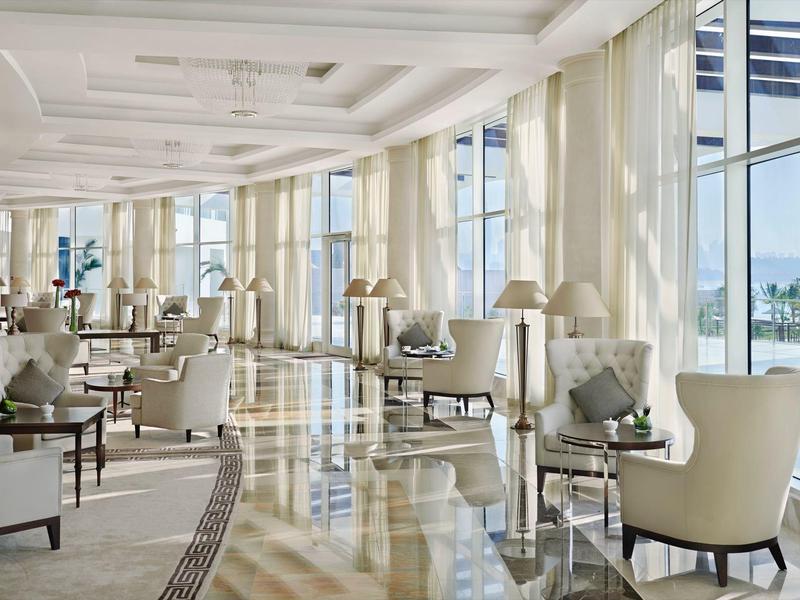 Eleganter heller Lounge-Bereich mit großen Fenstern, bequemen Sesseln und stilvollen Lampen.