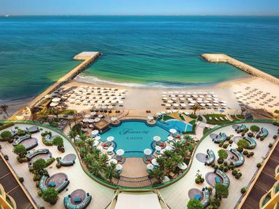 Luxuriöses Resort mit Pool, Liegestühlen und Strand mit klarem, blauem Wasser.