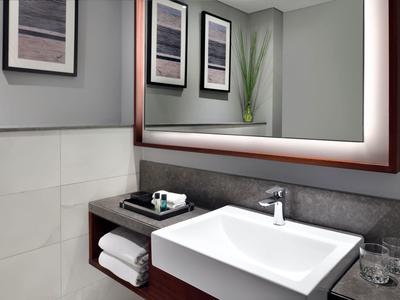 Modern hotel bathroom with large illuminated mirror and clean white sink.