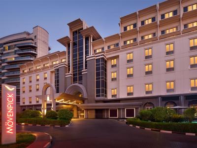 Modern hotel building with warmly lit windows and prominent entrance area at dusk.