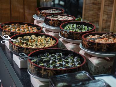 Buffet featuring various freshly prepared salads in brown bowls on a counter.