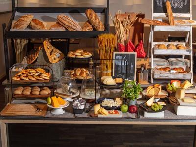 Bakery counter with various breads and pastries, wooden shelves, and fresh decor.
