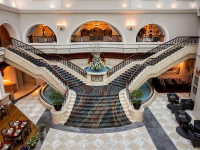 Elegant hotel lobby with double curved staircase and patterned carpet flooring.