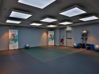 Spacious, modern fitness room with floor mats, exercise balls, and bright ceiling lights.