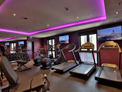 Modern gym with treadmills and equipment, ceiling lighting featuring pink accents.