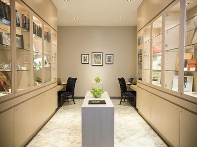 Salle moderne et simple avec étagères, deux chaises et une table centrale avec plante.