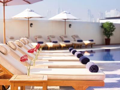 Chaises longues avec serviettes et fleurs au bord d'une piscine d'hôtel par temps ensoleillé.