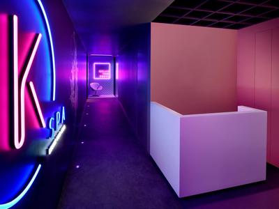 Korytarz z jasnym fioletowym i niebieskim oświetleniem neonowym w nowoczesnym wnętrzu hotelu.