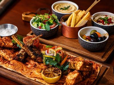 Assorted grilled dishes and sides arranged on a wooden board.
