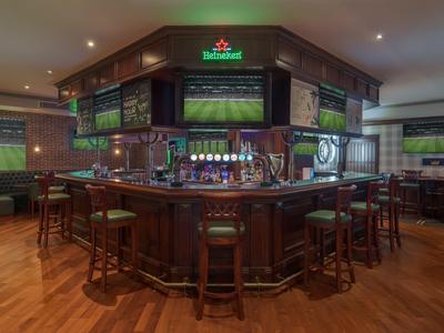 Bar area with wooden counter and stools in a cozy hotel restaurant.