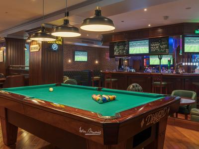 Interior of a hotel bar with a pool table and multiple TVs on the wall.
