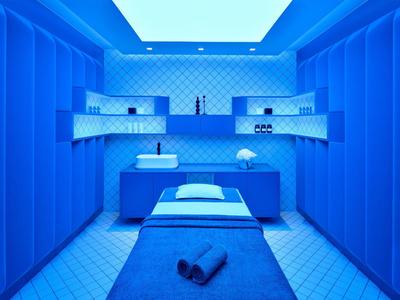Nowoczesny pokój zabiegowy spa z niebieskim oświetleniem i stołem do masażu.