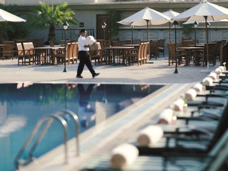 Jasny pokój hotelowy z dwoma łóżkami, biurkiem i fotelem przy dużym oknie.