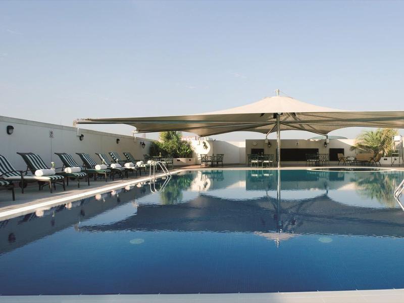 Nowoczesny basen z leżakami i parasolami obok czystego, niebieskiego basenu.