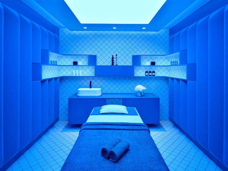 Nowoczesny pokój zabiegowy spa z niebieskim oświetleniem i stołem do masażu.