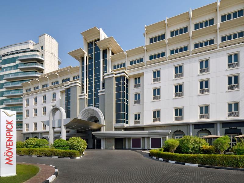 Nowoczesny hotel Mövenpick z zadbanym wejściem i roślinami biurowymi pod czystym niebem.