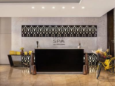 Moderne SPA-Rezeption mit schwarzem Tresen, dekorativem Wandpaneel und gelbem Fahrrad im Eingangsbereich.