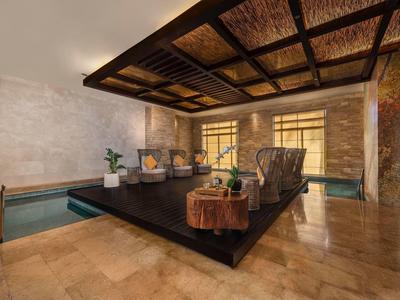 Moderner Wellnessraum mit bequemer Sitzinsel, Wasserbecken und warmem, natürlichem Licht.